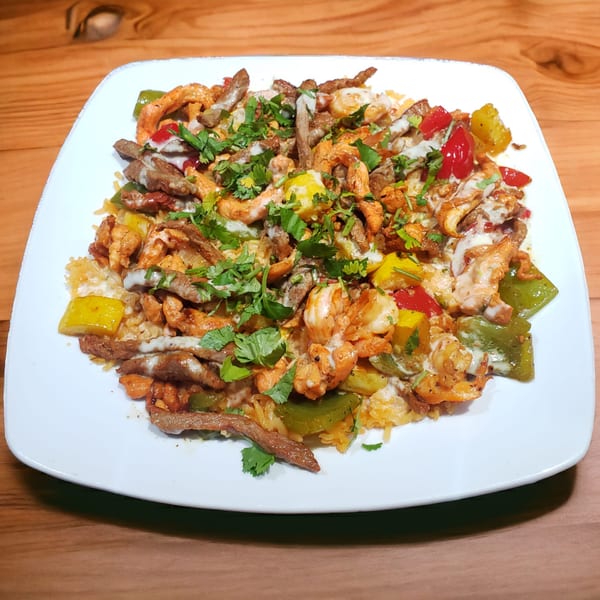 A Honduran dish with shrimp, beef, peppers, and cilantro on a white plate.