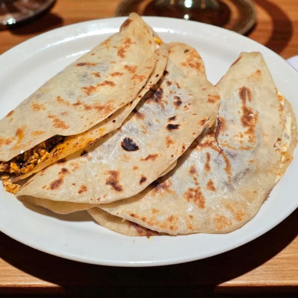 Three Honduran baleadas, folded tortillas filled with beans and cheese, on a white plate.